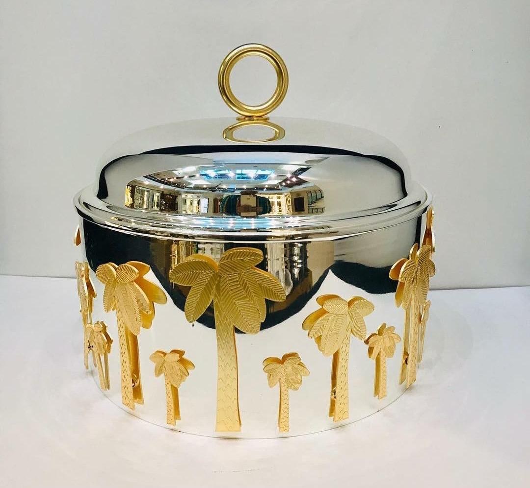 Polished silver domed server with gold palm-tree motifs around the base and a gold ring handle