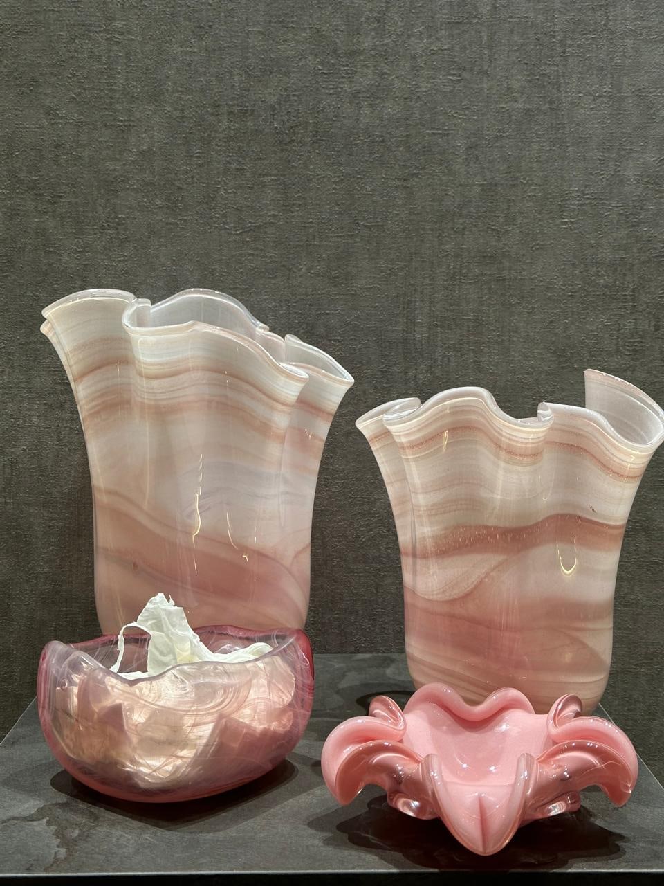 Pink marbled glass vases with wavy rims beside two matching glass bowls