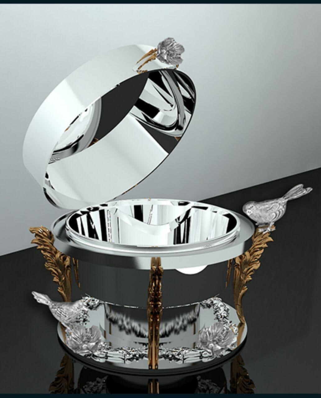 Round polished silver chafing dish on a gold stand with sculpted silver birds